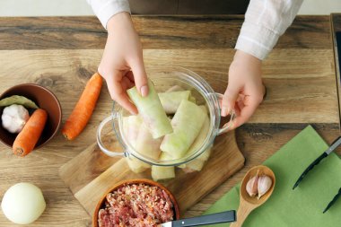 Ahşap masada içi doldurulmuş lahana dolu rulo pişiren kadın.