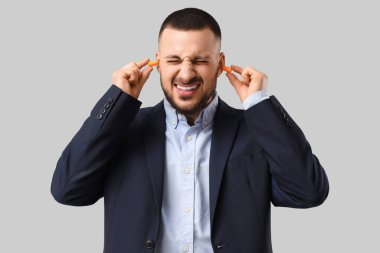 Gri arka planda gürültüden muzdarip genç işadamı