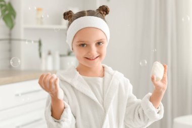 Banyosunda sabun ve köpükler olan küçük bir kız.