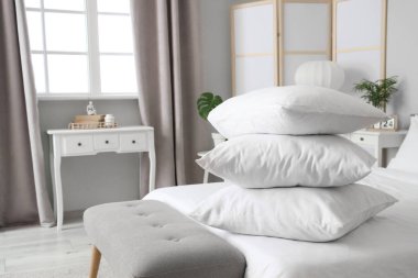 Beyaz battaniyeli rahat yatak ve şık yatak odasında yumuşak yastıklar, yakın çekim.