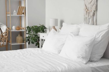 Beyaz battaniyeli rahat yatak ve şık yatak odasında yumuşak yastıklar.