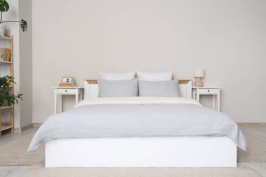 Gri battaniyeli rahat yatak ve şık yatak odasında yumuşak yastıklar.