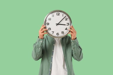 Yeşil arka planda duvar saati olan adam