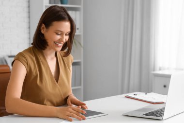 Ofisteki masada tablet bilgisayarla çalışan genç iş kadını.