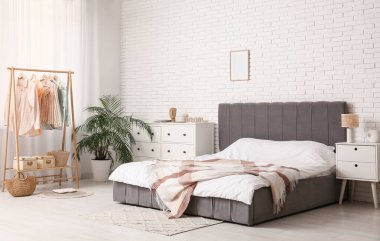 Yatak odasının içinde giysi rafı, tuvalet ve masa var.