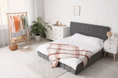 Yatak odasının içinde giysi rafı, tuvalet ve masa var.