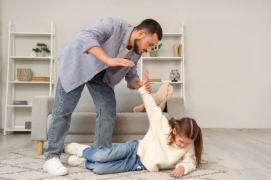 Kızgın baba evde kızını incitiyor. Aile içi şiddet kavramı