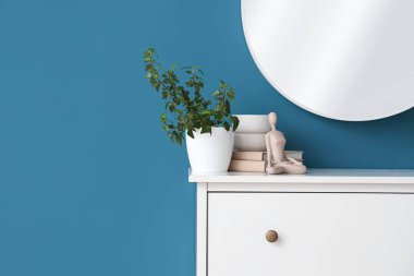 Dekorlu çekmeceler, mavi duvarlı ev bitkisi ve ayna. Yakın çekim.