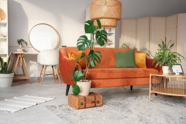 Kahverengi kanepesi, çiçekleri, sehpası ve aynası olan şık bir oturma odası.