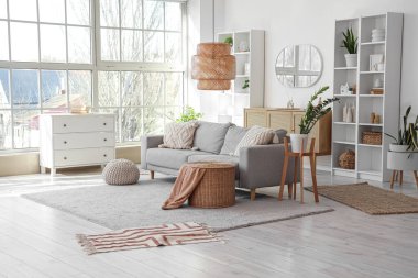 Gri kanepeli, raf üniteli ve aynalı aydınlık oturma odasının içi.