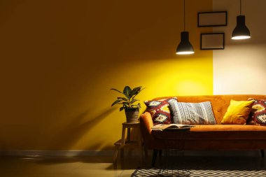 Kırmızı kanepesi, masası ve parlak lambaları olan karanlık oturma odasının içinde.