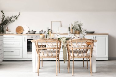 Güzel çiçekleri, okaliptüs dalları ve açık mutfakta mumları olan zarif bir masa.