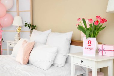 Yatak odasındaki kadınlar günü için laleli vazo, hediye ve tebrik kartı.