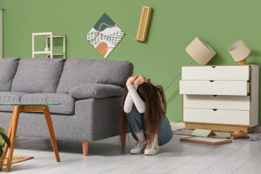 Deprem sırasında oturma odasındaki kanepede başını örten korkmuş genç kadın.