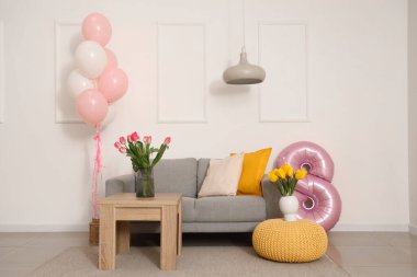Kadınlar Günü için dekore edilmiş oturma odasının içi kanepe, masa ve balonlarla dolu.
