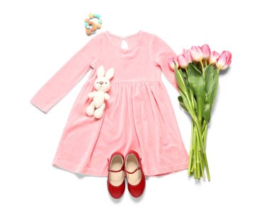 Tavşan oyuncağı ve beyaz arka planda laleleri olan küçük bir kız bahar kıyafeti.