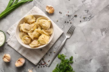 Bir kase lezzetli haşlanmış hamur köftesi, yeşil soğan ve gri arka planda maydanoz.