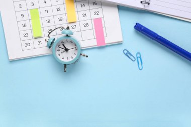 Mavi arkaplan üzerinde alarm saati ve kırtasiye ile metin için boşluk içeren bir takvim