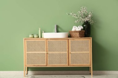 Çiçekli bir vazo, banyo malzemeleri ve banyonun iç tarafındaki çekmecelerin üzerine lavabo.