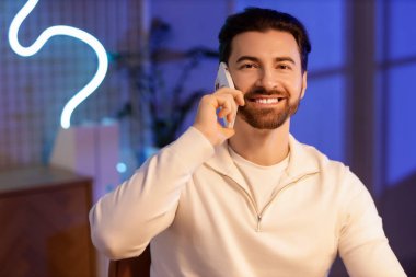 Geceleri ofiste cep telefonuyla konuşan yakışıklı bir adam.