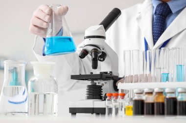 Matarası ve mikroskobu olan erkek bilim adamı laboratuvarda, yakın planda.