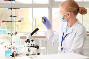 Laboratuvarda çalışan mikroskobu ve ampulü olan kadın bilim adamı.