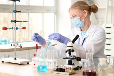 Laboratuvarda çalışan test tüpleri ve mikroskobu olan kadın bilim adamı.