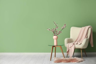 Beyaz koltuklu ve sehpanın üzerinde çiçek açan ağaç dalları olan şık bir oturma odası.