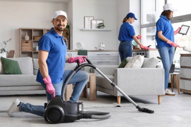 Oda da elektrikli süpürge kullanan erkek hademe.