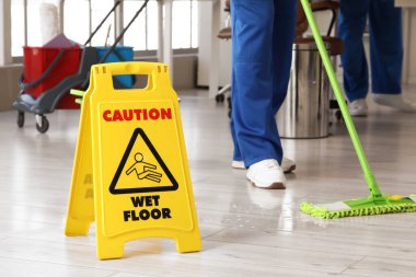 Kapıcının ofis zeminini paspaslamasına karşı uyarı işareti. Kapatma.