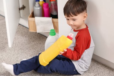 Mutfaktaki halının üzerinde duran deterjanı olan küçük çocuk. Tehlikedeki çocuk