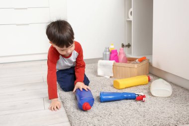 Mutfakta halıda deterjanı olan küçük bir çocuk. Tehlikedeki çocuk