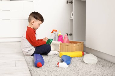 Mutfakta halıda deterjanı olan küçük bir çocuk. Tehlikedeki çocuk