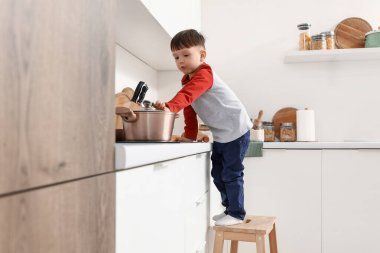 Mutfakta fırında tenceresi olan küçük bir çocuk. Tehlikedeki çocuk