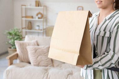 Evde kese kağıdıyla dolaşan genç bir kadın, yakın plan. Yemek dağıtım servisi.