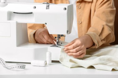 Atölyede kadın terzi elbise dikiyor, yakın plan.