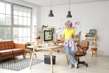 Ofisteki masada dizüstü bilgisayar ve grafik tabletle çalışan güzel bir web tasarımcısı