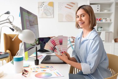 Ofisteki masalarda renk paletleri ile çalışan güzel kadın web tasarımcısı