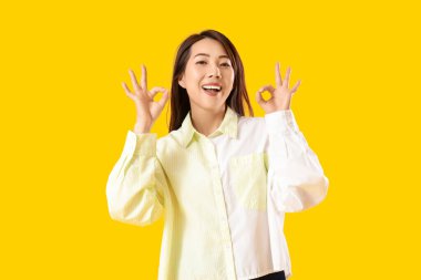 Genç Asyalı kadın sarı arka planda iyi görünüyor.