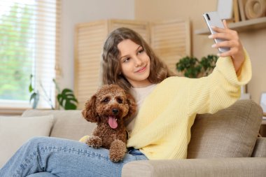 Kaniş köpeği olan genç bir kız evdeki kanepede selfie çekiyor.