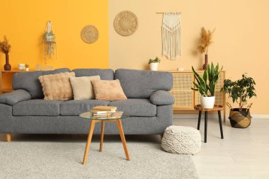 Rahat gri kanepe, puf ve masa aydınlık oturma odasının içinde.