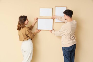 Bej duvarlara boş çerçeveler asan genç bir çift.