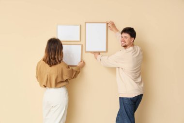 Bej duvarlara boş çerçeveler asan genç bir çift.