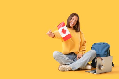 Kanada bayrağı ve sırt çantasıyla sarı arka planda oturan bayan öğrenci.