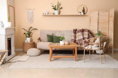 Şömineli, gri kanepeli ve hasır koltuklu aydınlık oturma odasının içi.