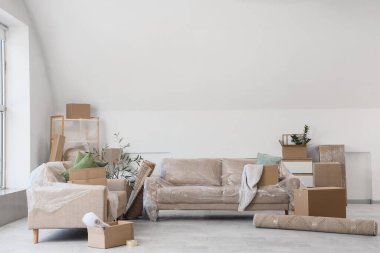 Taşınırken odada film ve karton kutularla kaplı kanepeler.