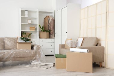 Taşındığı gün kanepeleri, dolabı ve karton kutuları olan oturma odasının içinde.