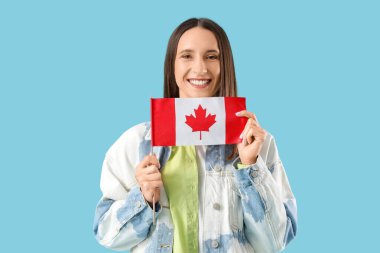 Mavi arka planda Kanada bayrağı olan genç bir kadın.