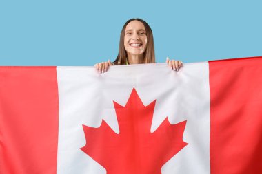 Mavi arka planda Kanada bayrağı olan genç bir kadın.