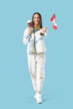 Kanada bayrağı ve mavi arka planda pasaportu olan genç bir kadın.